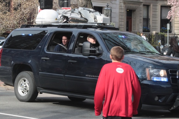 An SUV with U.S. Government plates and a roof-mounted satellite arrives at the scene. It was waved through toward the marathon finish line.